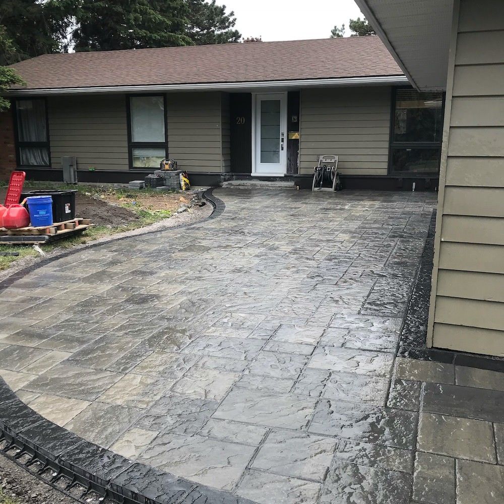 Wide curved paver driveway with a darker curved border leading to the front door of a one-storey house